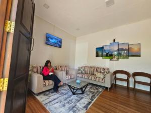 a woman sitting on a couch in a living room at Riverston Hideaway in Matale