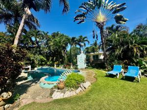 a pool in a yard with two chairs and a swimming pool at CasaLoca Cabarete Studio Apartment in Cabarete