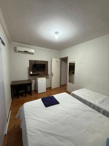 a bedroom with two beds and a desk and a tv at hotel paiol mutum in Nova Mutum +5 photos