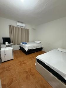 a room with two beds and a television in it at hotel paiol mutum in Nova Mutum