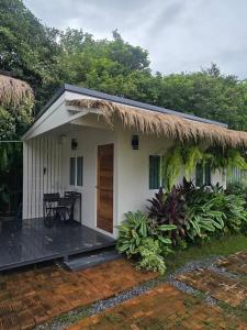 a small white house with a thatch roof at Chaba3 in Ban Nong Bua Noi