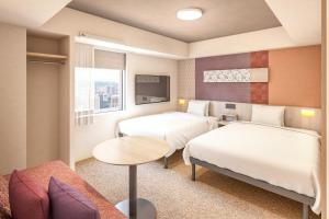 a hotel room with two beds and a table at たびのホテルlit豊川 in Toyokawa