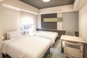 a hotel room with two beds and a desk at たびのホテルlit豊川 in Toyokawa