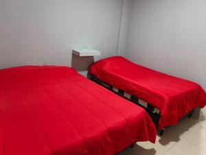 two beds in a room with red blankets at Hospedaje Don Antonio 1 in Tinogasta