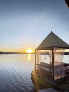a gazebo on a dock in the water at sunset at TiticacaMarkaLodge in Puno