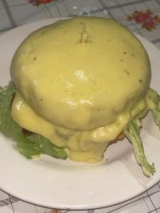 a sandwich covered in sauce on a white plate at Hotel GinaMar Ladrilleros in Buenaventura