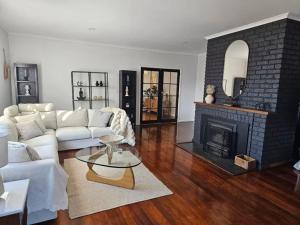 a living room with a white couch and a fireplace at Trawalla Farm Stays - Entire House and Large Pool Bar - Perfect for Groups in Bywong