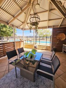 a patio with a table and chairs and a chandelier at Trawalla Farm Stays - Entire House and Large Pool Bar - Perfect for Groups in Bywong