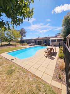 a swimming pool in a yard with a picnic table at Trawalla Farm Stays - Entire House and Large Pool Bar - Perfect for Groups in Bywong