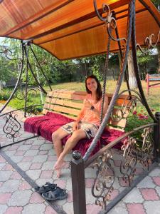 a woman sitting on a swing in a park at Fazenda guest house in Oktyabrʼskoye