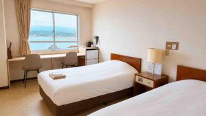 a hotel room with two beds and a window at Marine Hotel Harimo in Hamada