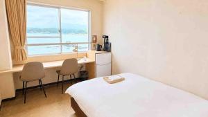 a bedroom with a bed and a desk and a window at Marine Hotel Harimo in Hamada