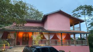 a pink house with a car parked in front of it at Pousada Refugio da Ilha Ilhabela in Ilhabela