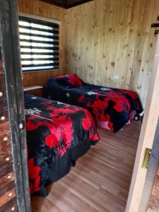 two beds in a room with wooden walls at Cabañas Alturas Don Gaspar in Recinto