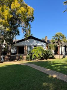 a house with palm trees and a grass yard at Gemstone Guest House in Klerksdorp