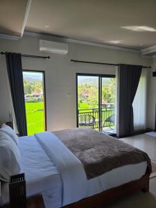 a bedroom with a large bed and a balcony at Bukit Luwih House in Munduk