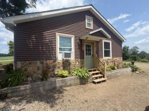 a small brown house with a stone wall at Cozy Creek Retreat in Waterford