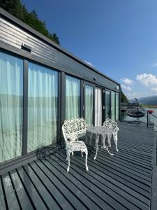 a deck with two chairs and a table on it at Black Swan Lakehouse in Bicaz
