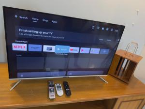 a flat screen tv sitting on a table with remote controls at Tiktoki Apartment 15C Kijal in Kijal