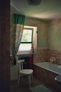 baño con bañera, silla y ventana en Ferienwohnung Guder en Bayerisch Gmain