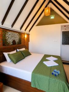 a bedroom with a large white bed with green sheets at The Oshin Villa in Trincomalee