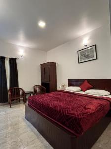 a bedroom with a large bed with a red blanket at Green woods stays in Ooty