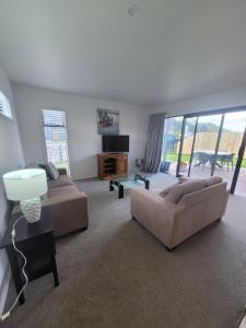 a living room with two couches and a television at Stylish townhouse in Te Aroha