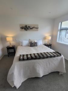 a bedroom with a large white bed with two lamps at Stylish townhouse in Te Aroha