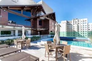 a patio with tables and chairs next to a pool at Apartamento completo e moderno com ar condicionado e piscina no centro do RIO in Rio de Janeiro