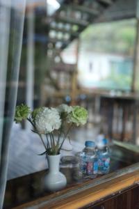 a vase with flowers on a table with bottles of water at Ơ MÂY ZING Homestay in Bắc Yên