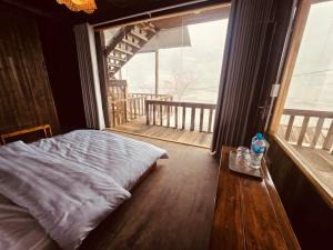 a bedroom with a bed and a table and a large window at Ơ MÂY ZING Homestay in Bắc Yên