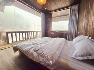 a bedroom with a large bed with a large window at Ơ MÂY ZING Homestay in Bắc Yên