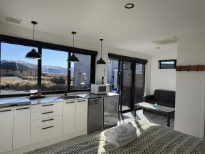 a kitchen with white cabinets and a large window at Simply Stunning Stars B in Lake Tekapo +5 photos