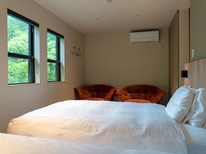 a bedroom with a large white bed and two chairs at 水杜のすみか大野屋 in Fukui