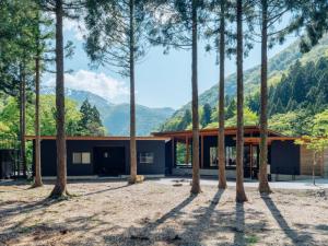 a house in the mountains with a group of trees at 水杜のすみか大野屋 in Fukui