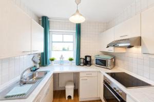 a kitchen with white cabinets and a sink and a window at Kleine Meereskrabbe in Werdum