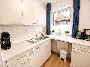 a kitchen with white cabinets and a sink and a window at Kleine Meereskrabbe in Werdum