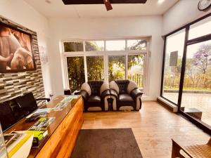 a living room with two leather chairs and a large window at The Raarees Mist Resort, Munnar - Nested in Nature's Lap in Munnar