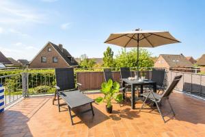 a patio with an umbrella and a table and chairs at Küstenlounge Dornumersiel in Dornum