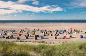 a beach with many colorful chairs in the sand at Küstenlounge Dornumersiel in Dornum