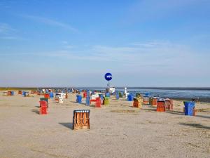 a beach with many colorful chairs on the sand at Küstenlounge Dornumersiel in Dornum +28 photos