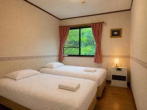 two beds in a room with a window at Anise Garden Lodge in Hakuba