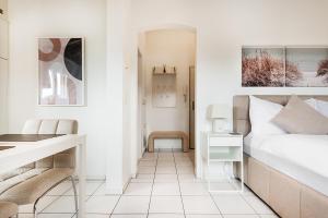a white bedroom with a bed and a desk at COZY 3 !Gratis Parken, Free Parking! in Weinfelden +3 photos