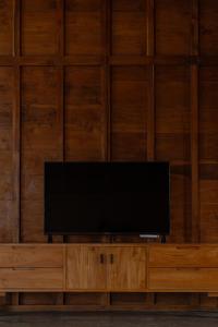 a flat screen tv sitting on top of a wooden wall at Cay's House Batukaras in Batukaras