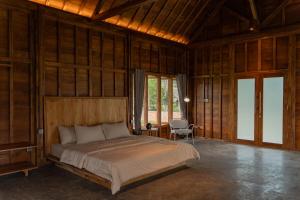 a bedroom with a bed in a room with wooden walls at Cay's House Batukaras in Batukaras