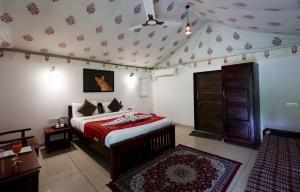 a bedroom with a bed with a red comforter at Jawai Empire Resort by Premier Hotels - Luxury Tent & Cottage Stay - Leopard Safari Near Jawai Dam in Pāli +101 photos