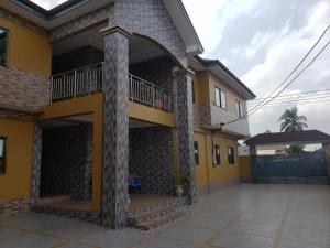 a yellow house with a porch and a balcony at EdJames Lodge in Ashaiman