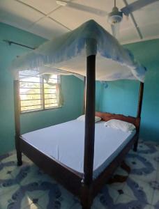 a bed with a canopy in a room at The Apple Bite in Malindi