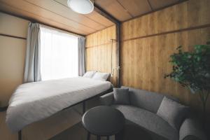 a small bedroom with a bed and a couch at Sand Village Kikuna in Kikuna