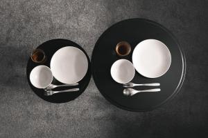 two black plates and spoons on a table at Sand Village Kikuna in Kikuna